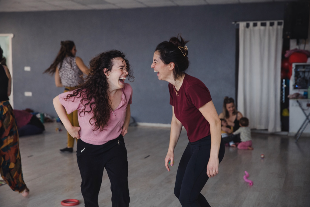 אמהות צוחקות ומשתחררות במהלך פעילות תנועה משותפת